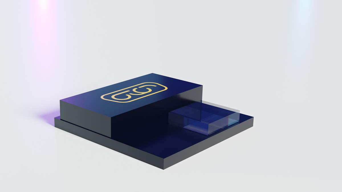 An elevated shot shows a wide, flat, dark blue block of a pedestal on a white surface, with a small transparent blue glass cube to the right. On the top of the taller pedestal is a symbol of two linked 'c's in a gold color.
