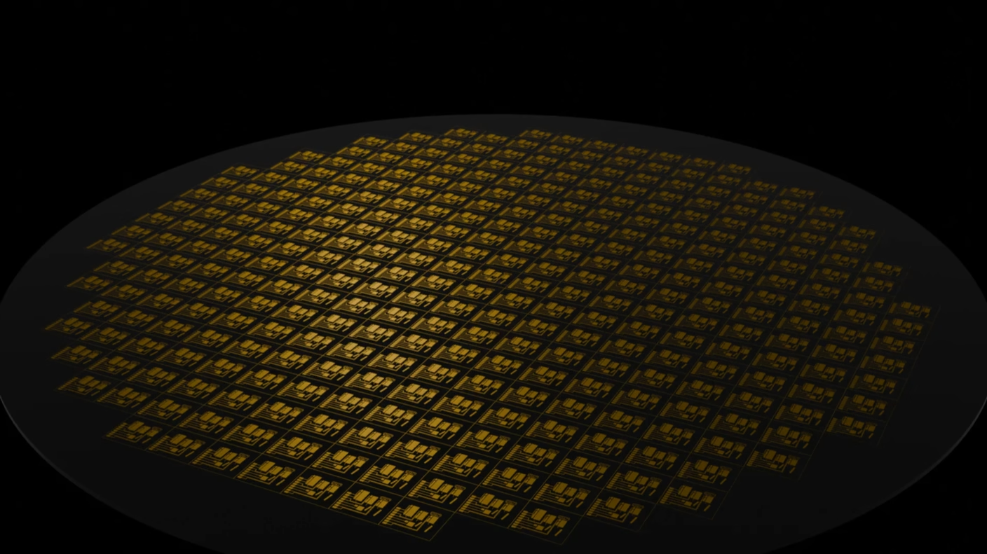 A circular silicon wafer is illuminated against a black background, featuring numerous intricate microchips arranged in a grid pattern.