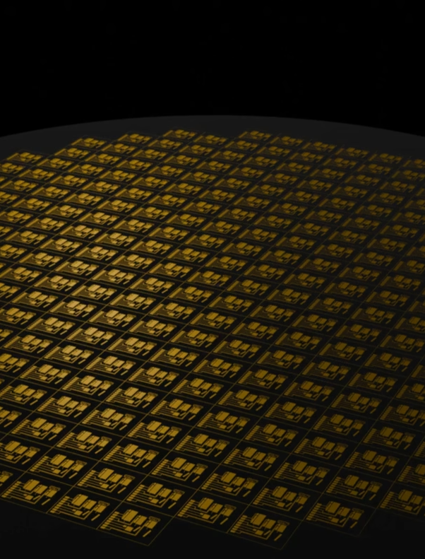 A circular silicon wafer is illuminated against a black background, featuring numerous intricate microchips arranged in a grid pattern.